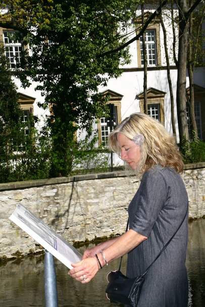 Mujer atractiva lee tablero de información con indicaciones de una vista en paderborn, nrw, Alemania - Foto, Imagen