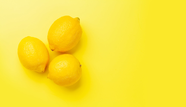 Fresh ripe lemons on yellow background. Top view flat lay with copy space - Фото, изображение