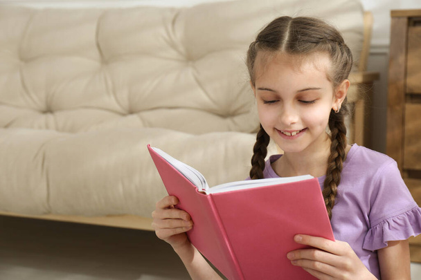 Cute little girl reading book at home. Space for text - Foto, imagen