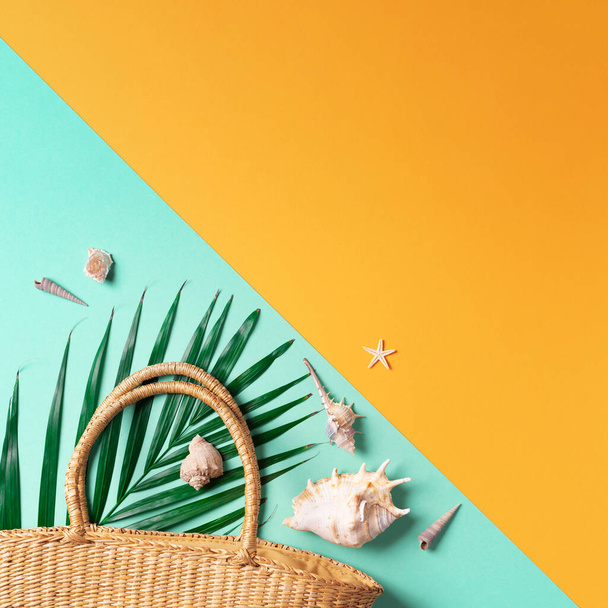 Summer travel concept with women straw bag, hat, palm leaves, shells on trendy yellow and green background. Top view. Copy space - Valokuva, kuva