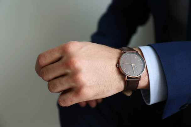 Businessman with luxury wrist watch on grey background, closeup - Foto, afbeelding