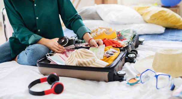 Unrecognizable woman with suitcase packing for holiday at home, coronavirus concept. - Фото, изображение