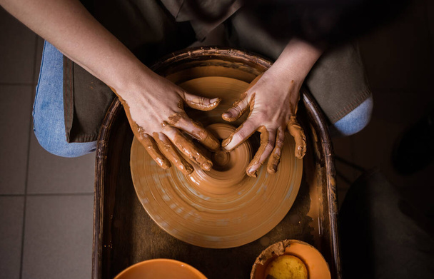 close-up of a person's hands making a bowl out of clay on a loom in a room - Photo, Image