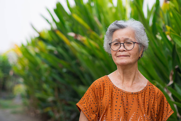 Muotokuva vanhusten nainen lyhyet valkoiset hiukset seisoo hymy ja katsot kameraa puutarhassa. Vanhat ihmiset terveitä ja on myönteisiä ajatuksia elämästä tehdä hänet onnelliseksi joka päivä. Terveydenhuollon käsite - Valokuva, kuva