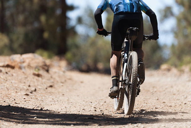 Горный велосипедист на велосипедной однопутной тропе, вид сзади на горного велосипедиста. Велогонка - Фото, изображение