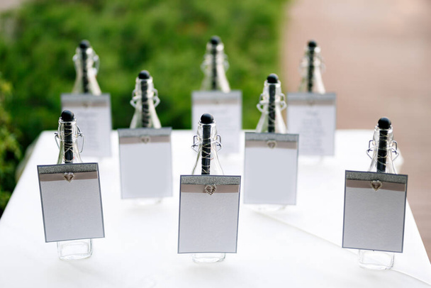 Botellas selladas con carteles en blanco sobre una mesa cubierta con un mantel blanco - Foto, Imagen