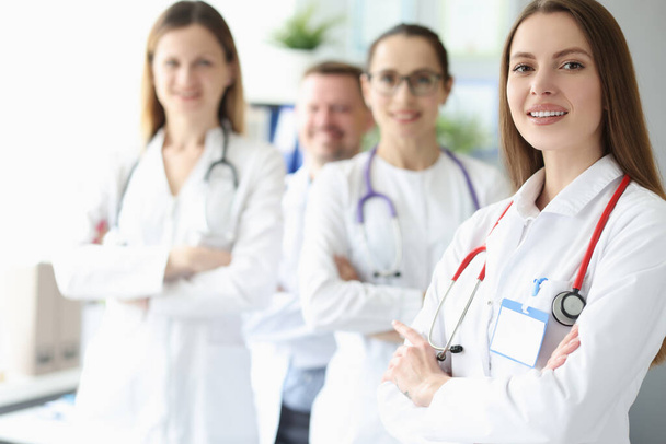Portrait of young smiling woman doctor on background of colleagues - Foto, Imagem