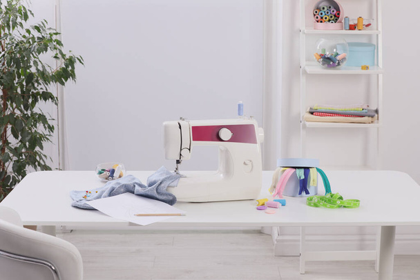 Modern sewing machine, fabric and accessories on table indoors - Foto, Imagen