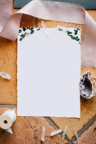 Een blanco wit briefhoofd ligt op een stenen tegel omlijst door een lint, een schelp en een draadje - Foto, afbeelding