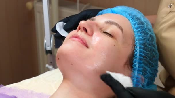 Cosmetoloog arts vegen vrouw gezicht maakt gebruik van katoen pads na peeling procedure. De dokter maakt schoonheidsbehandelingen in de kosmetologische kliniek. Zorg voor de gezichtshuid - Video