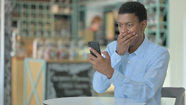 El hombre africano molesto que tiene pérdida en el teléfono inteligente en Café  - Foto, Imagen
