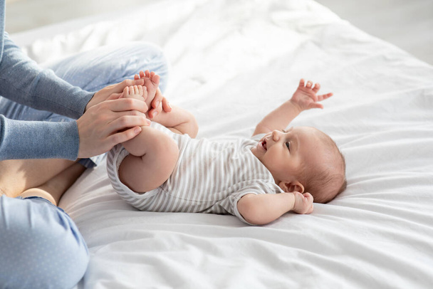 Törődő anya csinál torna az újszülött baba az ágyban otthon - Fotó, kép
