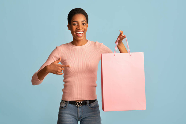 季節販売。陽気なアフリカの女性は保持し、空白のショッピングバッグを指して - 写真・画像
