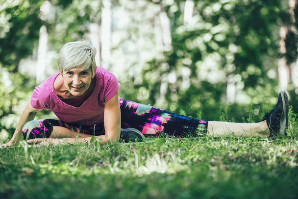 Felice donna matura che pratica yoga nel parco. Stile di vita attivo - Foto, immagini