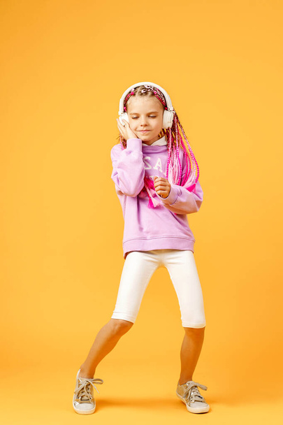 Adorable child in rounded glasses with pink dreadlocks listen to - Foto, Imagem