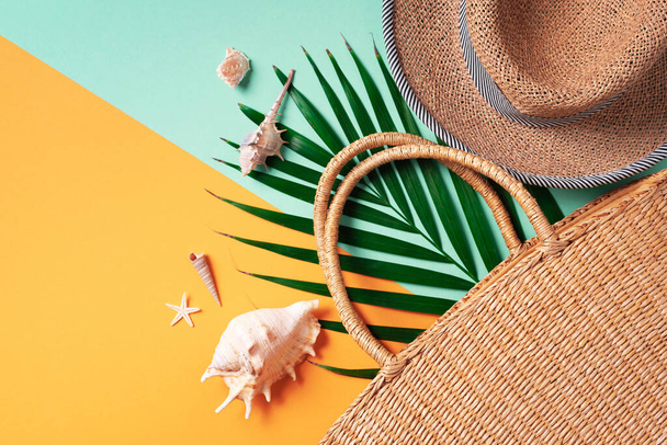 Summer fashion flat lay. Stylish straw bag, hat, palm leaves, shells on trendy yellow and green background. Top view. Copy space. Sustainable lifestyle. Zero waste, plastic free concept. - 写真・画像