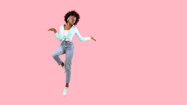 Bushy Black Woman Jumping pozowanie w powietrzu, różowe tło, Panorama - Zdjęcie, obraz