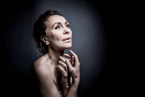 portrait of a sensual fifty year old woman on grey studio background - Photo, Image