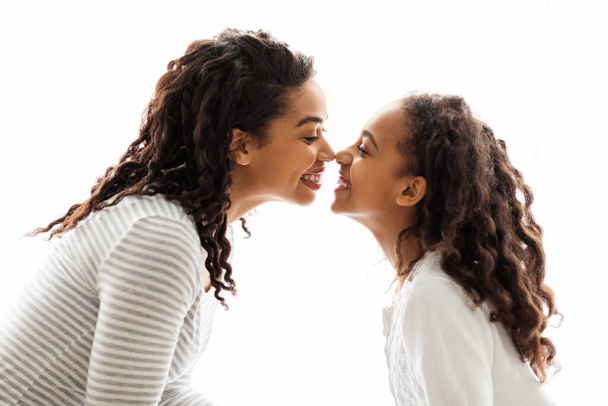 Чёрные мама и дочь трогают друг друга носами. - Фото, изображение