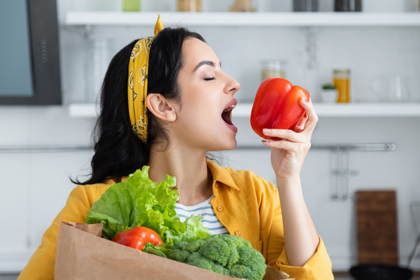 young brunette woman biting red bell pepper - Photo, Image
