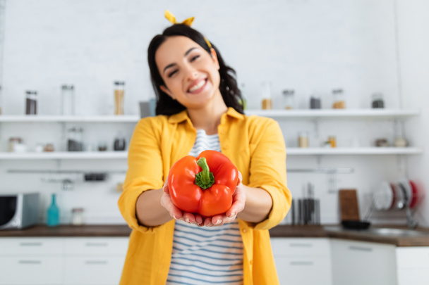 blurred and happy young woman holding red bell pepper  - Фото, изображение