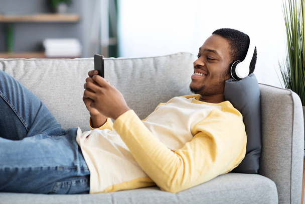 Veselý africký Američan sledování videa na mobilním telefonu - Fotografie, Obrázek