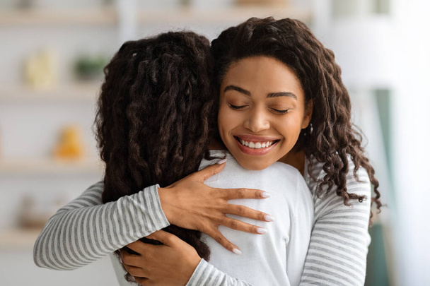Loving black mother hugging her daughter, home interior - Photo, Image