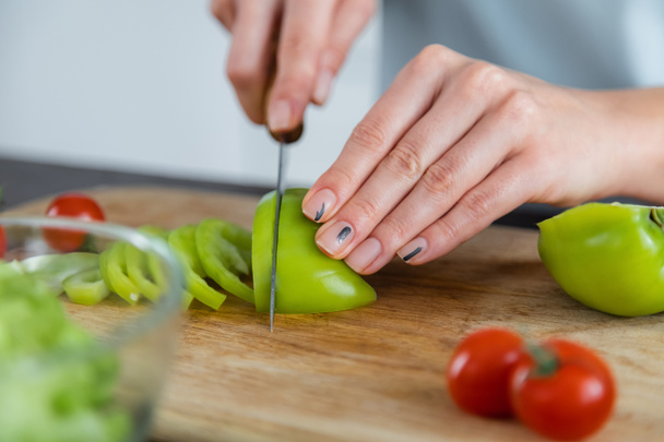 close up of woman cutting ripe bell pepper on chopping board  - Photo, Image