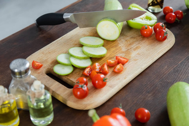 sliced zucchini near cherry tomatoes on wooden chopping board  - Fotoğraf, Görsel