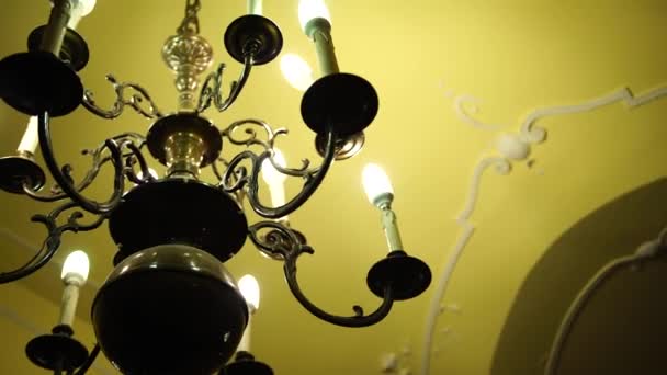 天井とキャンドルライト電球とバロック様式のブラックメタルシャンデリア. - 映像、動画