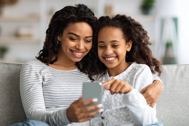 Happy african american mother and kid using smartphone together - Foto, imagen