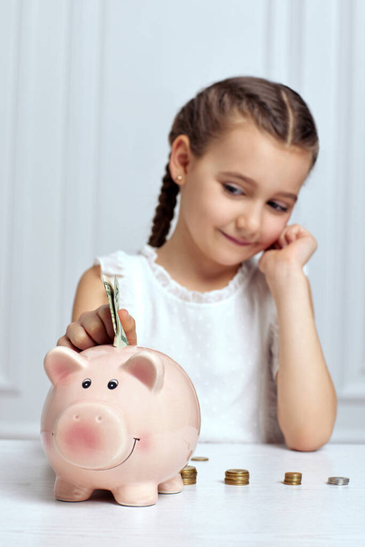 Little child girl with piggy bank at home - Fotó, kép