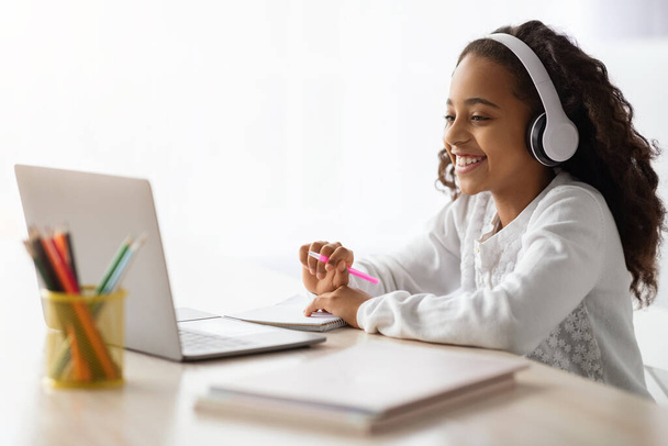 Веселая школьница с онлайн-уроком, с помощью ноутбука дома - Фото, изображение