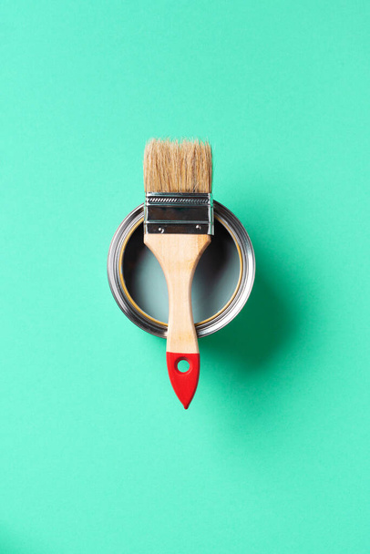 Paint brush and open paint can with on trendy green background. Top view, copy space. Appartment renovation, repair, building and home design concept. - Photo, Image