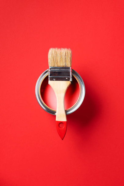 Brush and open paint can on trendy red background. Top view, copy space. Appartment renovation, repair, building and home design concept. - Фото, зображення