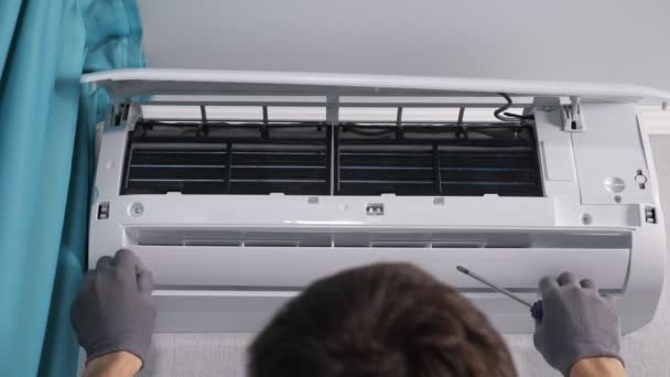 Man werknemer controleert airconditioner deksel en haalt schroeven - Video