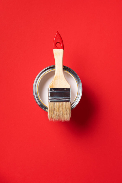 Brush and open paint can on trendy red background. Top view, copy space. Appartment renovation, repair, building and home design concept. - Photo, Image