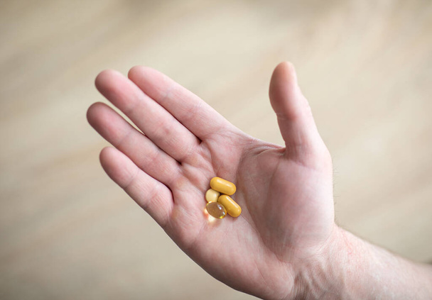 Vitamíny a doplňky. Muž drží tablety v pravé ruce. Pilulky v ruce představující koncept zdraví, pomoci a medicíny - Fotografie, Obrázek