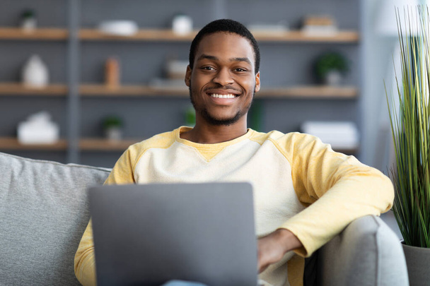 Closeup of cheerful black guy using laptop - Photo, Image