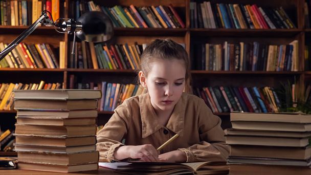 Jovencita cansada con chaqueta marrón escribe material de libro - Foto, imagen