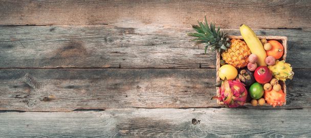 Rattan box full of exotic thailand fruits - pineapple, pitahaya, kiwano, african horned melon, tamarillo fruit, granadilla, feijoa, salak, snake fruits, maracuya, rambutan, lychee, longan, tamarind - Foto, imagen