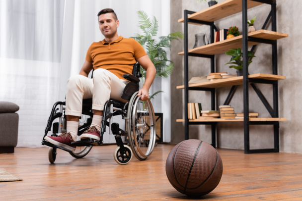 selective focus of basketball near young handicapped man sitting in wheelchair - Φωτογραφία, εικόνα
