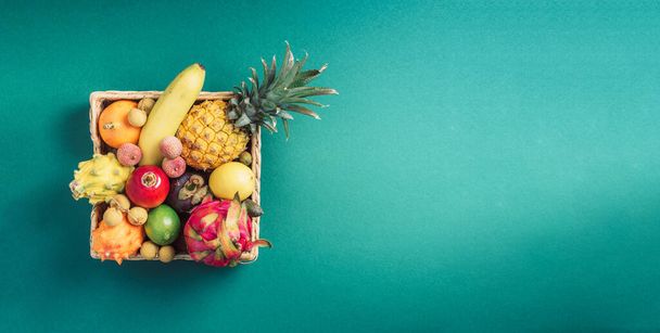 Rattan box full of exotic thailand fruits - pineapple, pitahaya, kiwano, african horned melon, tamarillo fruit, granadilla, feijoa, salak, snake fruits, maracuya, rambutan, lychee, longan, tamarind - Фото, зображення