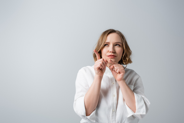 curious overweight woman in white shirt pointing with fingers isolated on grey  - Foto, Imagen