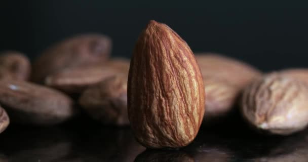 Makro záběr loupané pražené mandlové ořechy s pohyblivým světlem s tmavým pozadím - Záběry, video