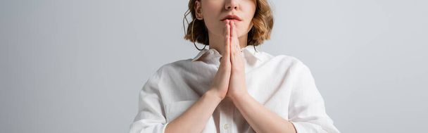 kivágott kilátás fiatal túlsúlyos nő fehér ing imádkozó kezét elszigetelt szürke, banner - Fotó, kép