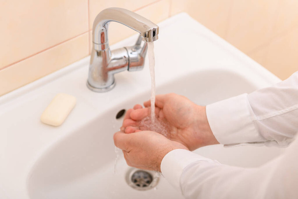 lavagem das mãos com sabão ou gel sob água corrente no lavatório, limpeza e higiene, mãos masculinas vestidas com uma camisa branca - Foto, Imagem