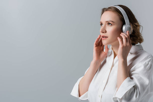 plus size woman in wireless headphones listening music isolated on grey - Photo, image