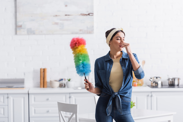 Hausfrau mit Staubbürste niest in Küche  - Foto, Bild