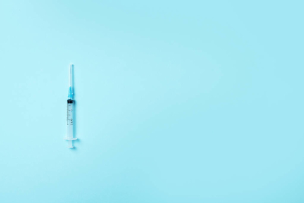 Syringe and needle on blue background. Injections and vaccination concept. Health protection equipment during quarantine Coronavirus pandemic - Photo, image